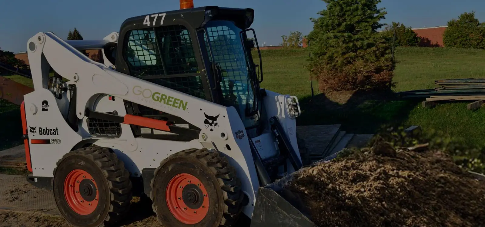 Compact loader beside a soil area